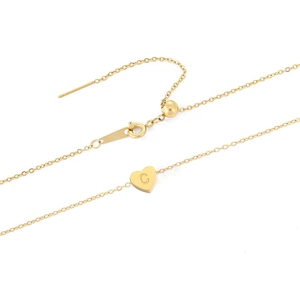 Gros plan d'un pendentif coeur doré avec gravure lettre C sur chaîne en acier inox