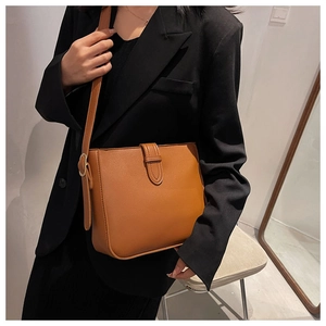 Brown leather crossbody bag detail on model wearing a black blazer for a retro style look