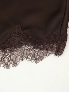 Detailed macro shot of dark brown satin fabric with delicate lace trim on a dress