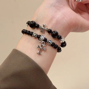 Détail de bracelets en perles noires avec pendentifs croix gothiques vintage