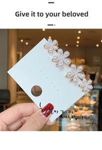 Macro detail of elegant pearl flower hair clips with golden metal base on a card