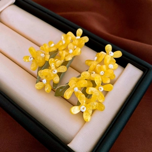 Macro shot of yellow flower earrings with green leaves in a black jewelry box