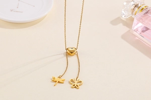 Détail du collier en Y doré avec curseur coeur, pendentifs libellule et papillon
