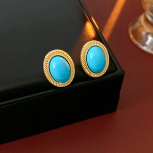 Close-up of vintage oval turquoise stud earrings with twisted gold metal edges in box