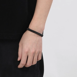 Detail shot of a matte black C-shaped woven stainless steel bracelet on a male wrist