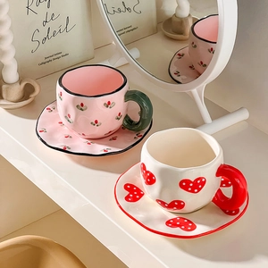Detail of two handmade heart and flower ceramic coffee cup and saucer sets on a shelf