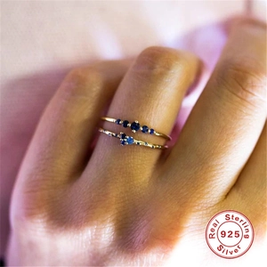 Macro shot of 925 sterling silver gold rings with blue sapphires on hand