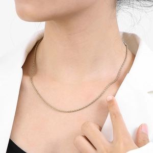 Gros plan d'un collier en chaîne torsadée bicolore or et argent porté par un mannequin