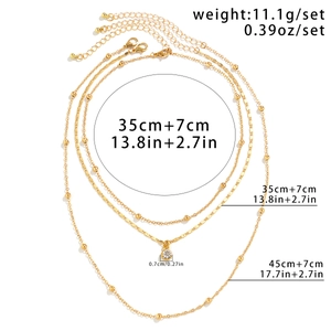 Detailed view of layered gold necklace with rhinestone pendant and length measurements
