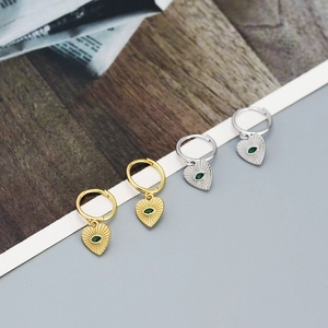 Detail of silver heart hoop earrings with green evil eye charms in gold and silver