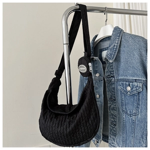 Detail of black quilted crescent shoulder bag with a small fashion pouch on the strap