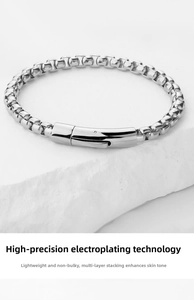 Close-up of a silver stainless steel box chain bracelet with a polished lobster clasp