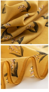 Detailed macro view of yellow silk-like fabric with floral print and fine stitching