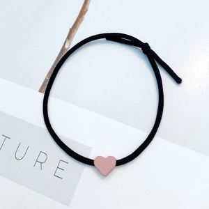 Minimalist elastic hair tie with pink heart pendant used as a stylish bracelet