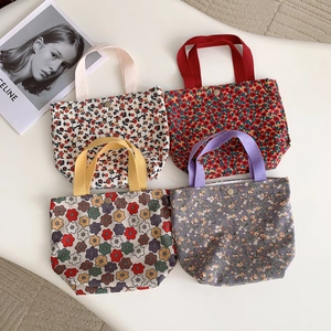 Flat lay of four vintage corduroy lunch bags featuring different floral patterns and snap buttons