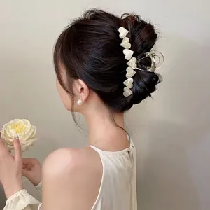Elegant clear hair claw clip with cream heart accents for loose bun hairstyles