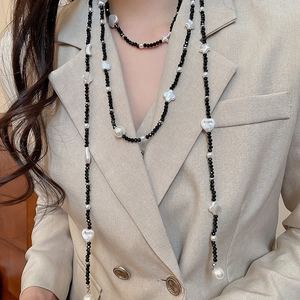 Detail of layered black and white beaded necklace with stars and pearls on a blazer