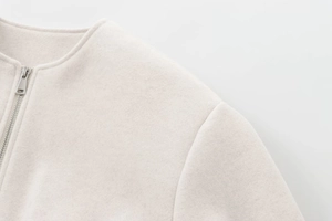 Détail macro du tissu en laine blanc cassé avec fermeture éclair argentée sur la veste