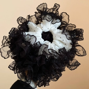 Détail de la dentelle noire et du tissu à pois blancs sur le chouchou élégant
