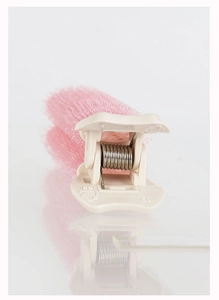 Close-up of pink hair root clip with soft bristles and beige plastic handle on white surface