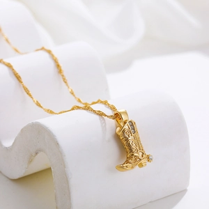 Macro view of 18K gold stainless steel western boot pendant with zircon and floral relief