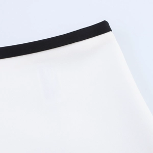 Detail view of white fabric with black contrast trim and precise stitching on the suit