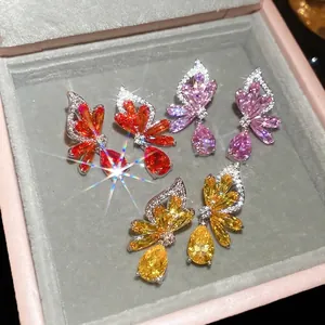 Three pairs of colorful butterfly zircon earrings on gray velvet inside a pink jewelry box