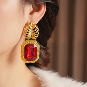 Boucles d'oreilles vintage avec feuille dorée et grosse gemme rouge sur un modèle