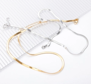 Detailed macro view of gold and silver flat snake chains with lobster clasp and extender