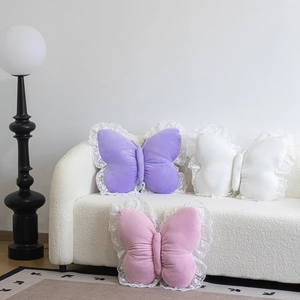 Plush butterfly pillows with lace edges in purple, pink, and white on a sofa