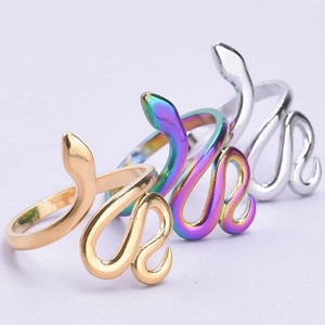 Detailed view of snake-shaped rings in gold, silver, and rainbow finishes on a textured surface