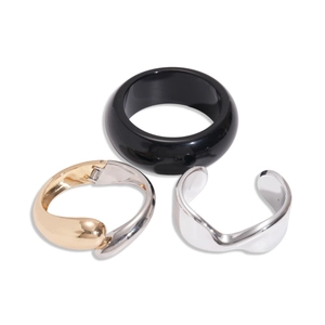 Three geometric metallic and resin cuff bracelets in black and gold on a white background