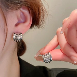 Macro view of rippled silver geometric earrings featuring a modern wavy metal texture