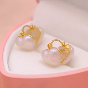 Detail of heart-shaped pearl earrings with gold finish inside a pink jewelry gift box