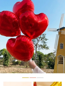Glossy red heart-shaped foil balloon for wedding decor against an outdoor blue sky background
