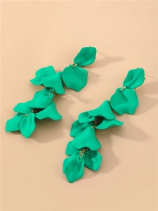 Détail de boucles d'oreilles pétales vert sarcelle avec liens dorés sur fond beige
