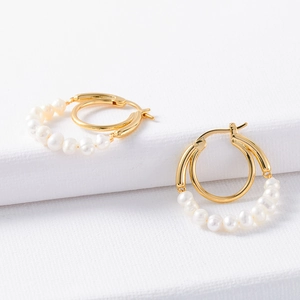 French bohemian gold hoop earrings with natural white pearls on white textured background