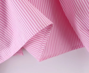 Dettaglio del tessuto in cotone a righe rosa e bianche con cuciture di pregio sull'orlo