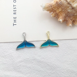 Detailed view of enamel mermaid tail charms in blue and cyan for jewelry making