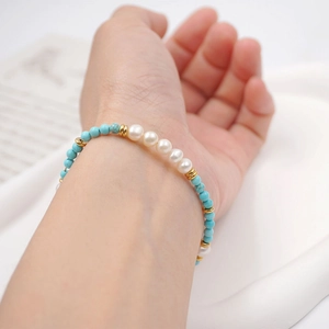 Baroque pearl and turquoise beaded bracelet with gold accents worn on a wrist