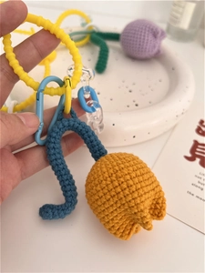 Macro detail of handmade crochet tulip pendant with orange flower and blue lanyard