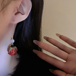Détail de boucles d'oreilles rose rouge avec feuilles vertes et perle blanche sur chaîne