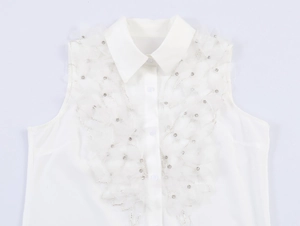 Détail d'un chemisier blanc sans manches en mousseline avec plumes et strass chic