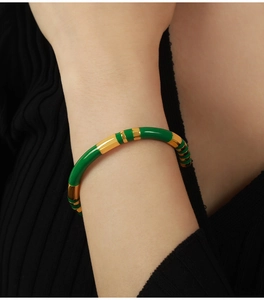 Close-up of green enamel and gold titanium steel bangle bracelet on model's wrist