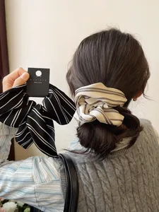 Detailed view of striped satin scrunchies and bow hair clips in black and white patterns