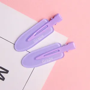 Close-up of two purple matte hair clips with Grape text on a pink and white background