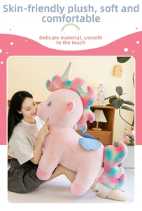 Close-up of the giant pink unicorn plush toy with rainbow mane and soft blue wings