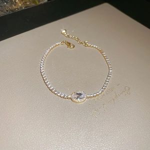 Macro shot of gold tennis bracelet with oval zircon centerpiece and adjustable chain