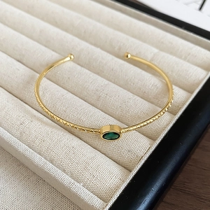 Détail d'un bracelet ouvert plaqué or 18k avec pierre verte et textures vintage fines