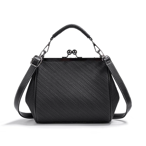 Detailed view of black woven texture on retro frame bag with leather handle and clasp